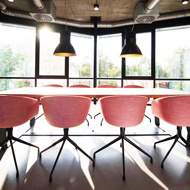 A modern conference room with bright pink chairs and large overhead lights