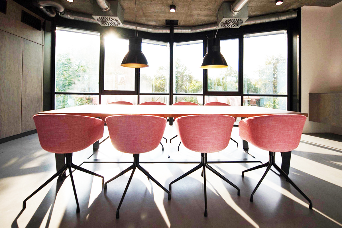 A modern conference room with bright pink chairs and large overhead lights