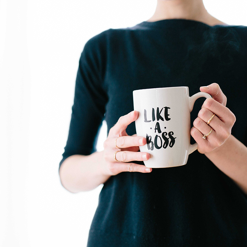 A woman holding a coffee cup that says 'Like a boss'
