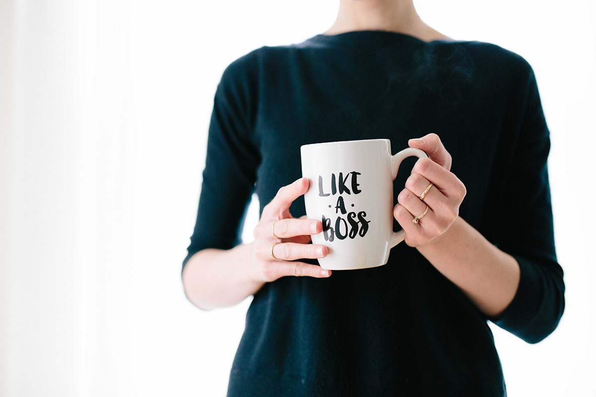 A woman holding a coffee cup that says 'Like a boss'