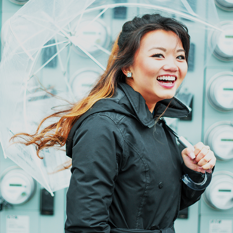 A smiling woman walking while holding an umbrella