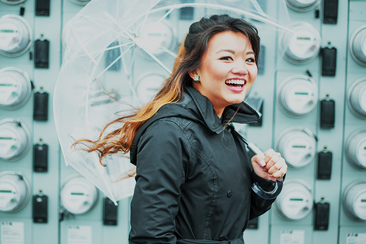 A smiling woman walking while holding an umbrella