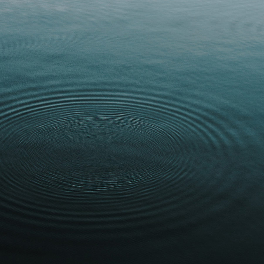 A body of blue water with circles of ripples on the surface