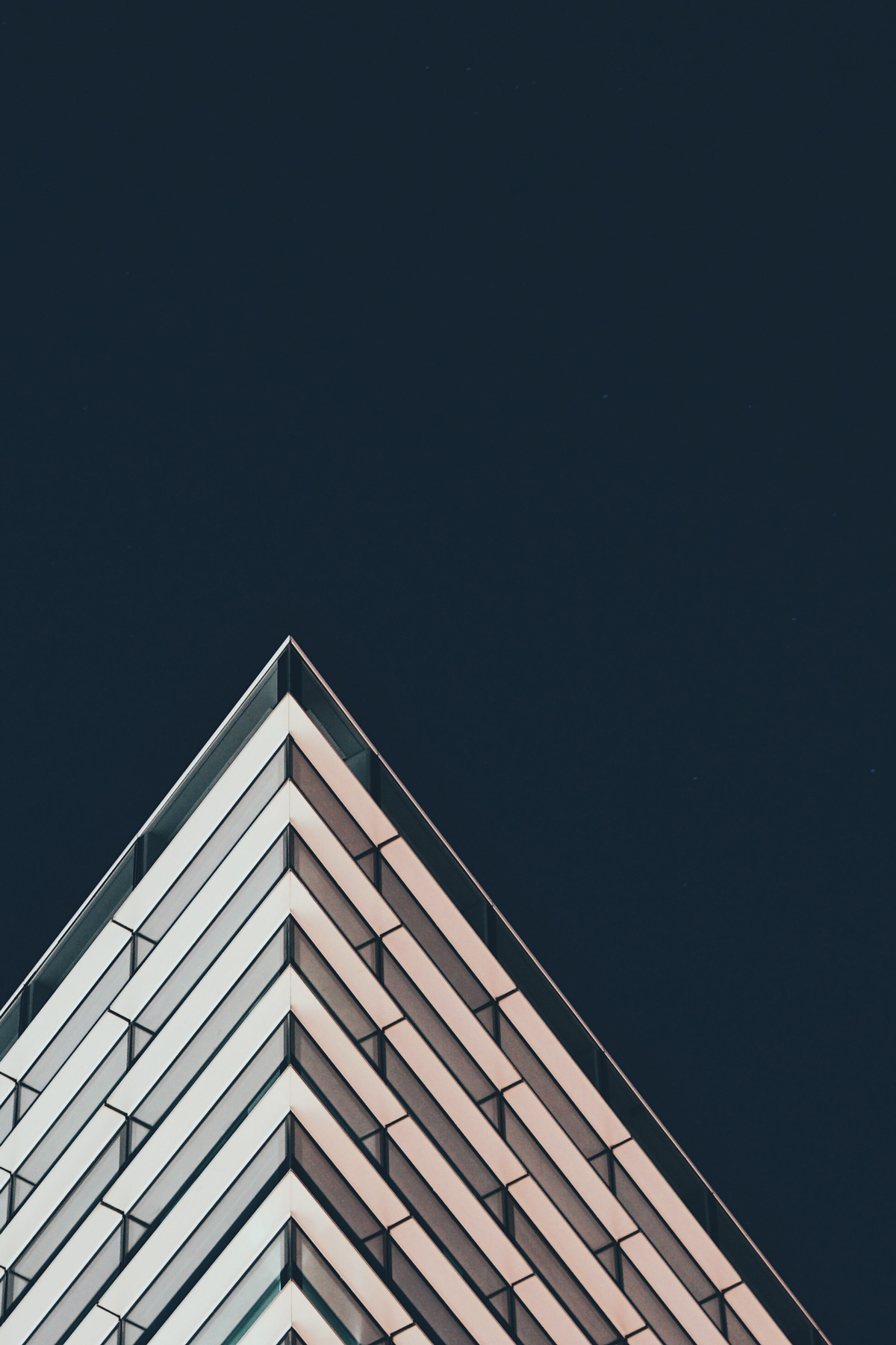 The corner of a tall building against a dark blue sky