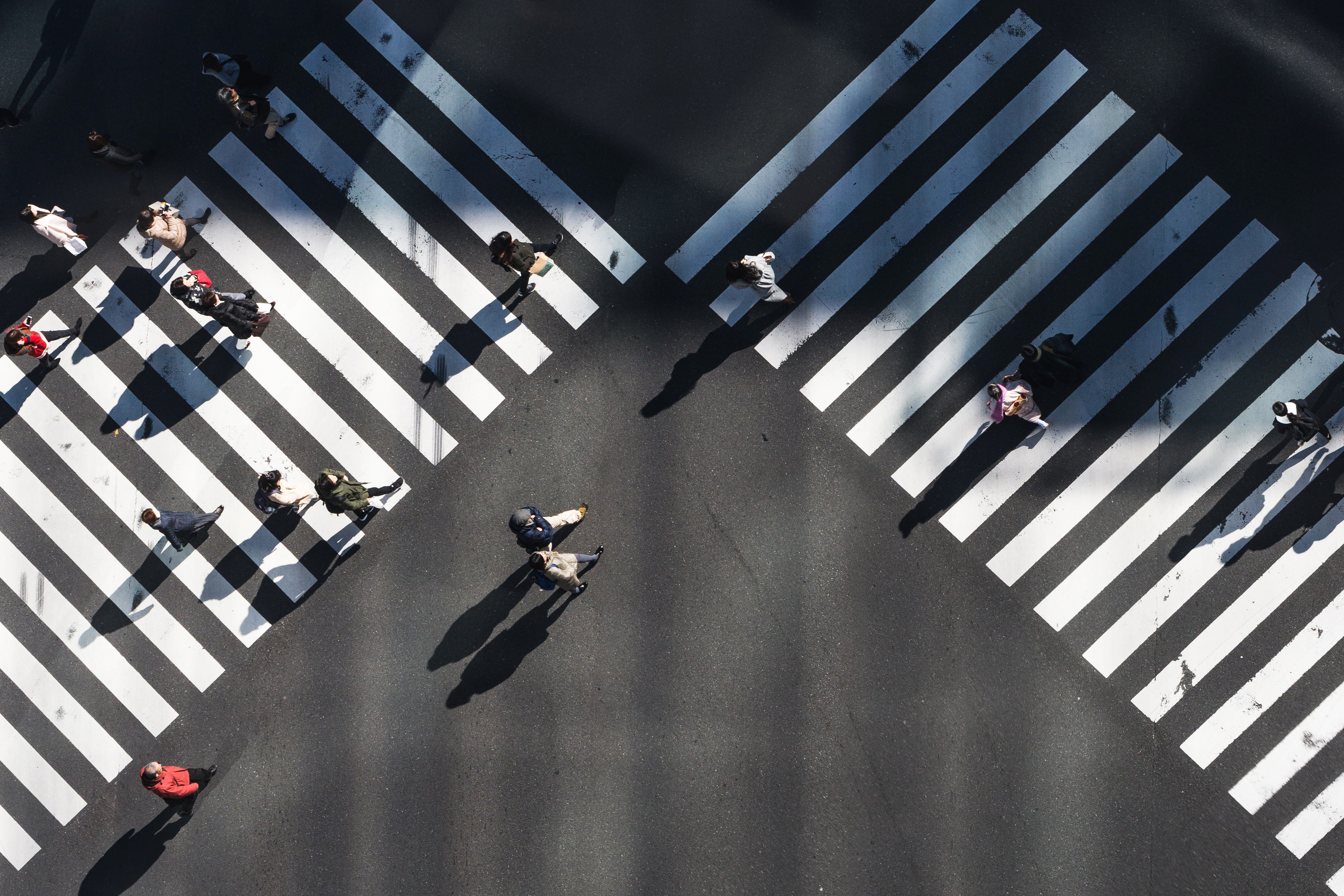 An aerial image of multiple people walking across two pedestrian crossings